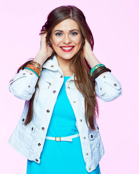 smiling woman with long hair in white jacket and blue dress posing on pink background - Foto, Imagem