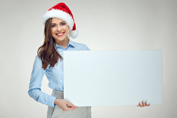 Businesswoman wearing blue shirt and santa hat holding white sign board  - Foto, afbeelding