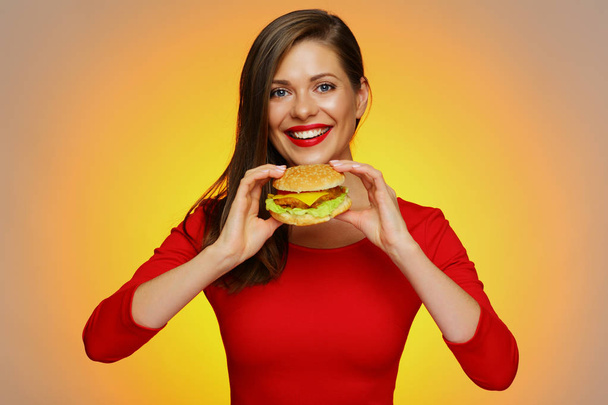 happy woman in red dress holding burger on yellow background  - Фото, изображение