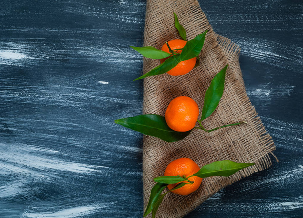 mandarini con foglie verdi su tela su fondo di legno blu, primo piano, vista dall'alto, concetto di frutta arancione
 - Foto, immagini