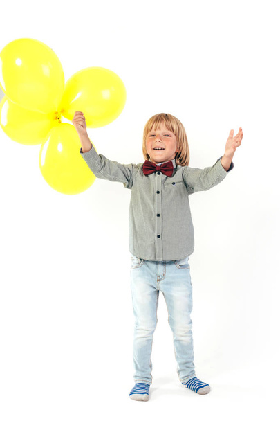 Stylish little boy dressed in red bow tie holding air balloon isolated on white background. Smile. - Foto, imagen