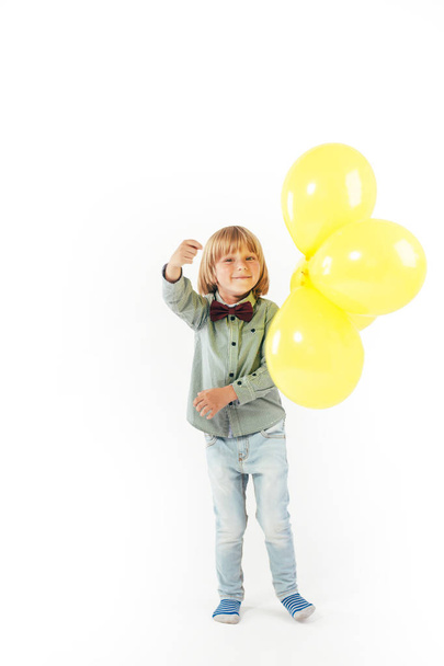 Stylish little boy dressed in red bow tie holding air balloon isolated on white background. Smile. - Foto, Imagem