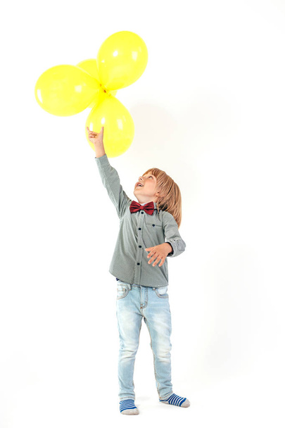 Stylish little boy dressed in red bow tie holding air balloon isolated on white background. Smile. - Fotoğraf, Görsel
