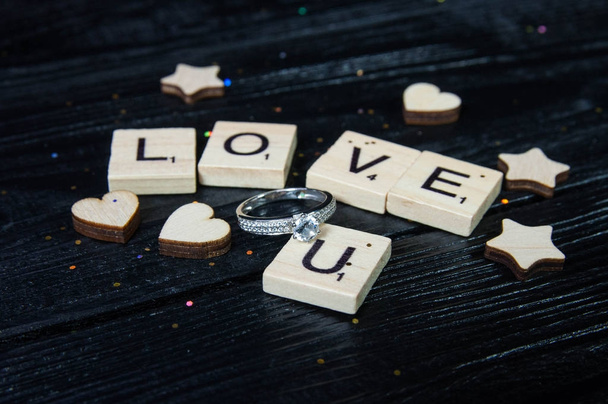 Ξύλινο γράμμα της αλφαβήτου μπλοκ κεραμίδια έννοια αγάπης για την ημέρα του Αγίου Βαλεντίνου με το γαμήλιο δαχτυλίδι στο ξύλινο πλαίσιο - Φωτογραφία, εικόνα
