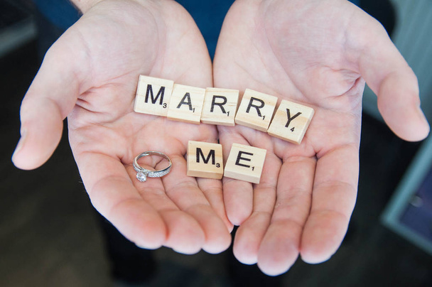 Letra del alfabeto bloques de madera azulejos concepto de amor para el día de San Valentín con anillo de bodas en las manos del hombre
 - Foto, Imagen