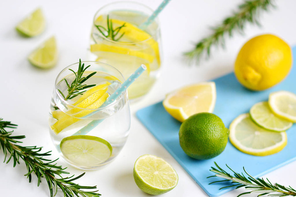Gläser mit Süßwasser Rosmarin Zitrone Limetten Früchte weißer Hintergrund Getränk gesunde Lebensweise - Foto, Bild