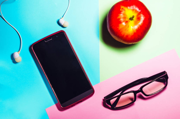 telefone e óculos. espaço de trabalho. auscultadores para ouvir música. tecnologias. comida, maçã vermelha
 - Foto, Imagem