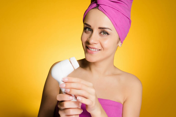happy woman with towel on her head holds in her hand a brush for deep cleaning - Фото, зображення