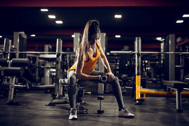 beautiful sporty young woman exercising with dumbbell in gym - Photo, Image