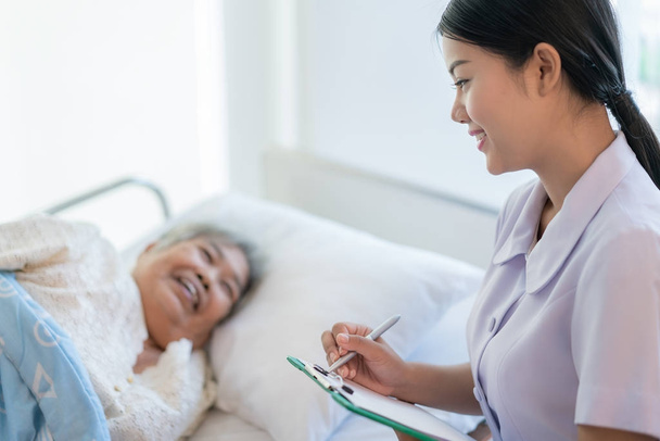 Азиатская медсестра проверяет историю болезни пожилых пациентов
 - Фото, изображение