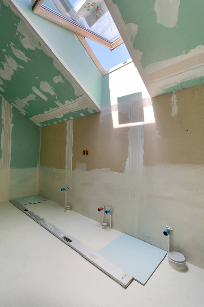 Finishing-Arbeiten an renovierten Wohnung. Einbau von Rohren im Badezimmer mit Mansardenfenster - Foto, Bild