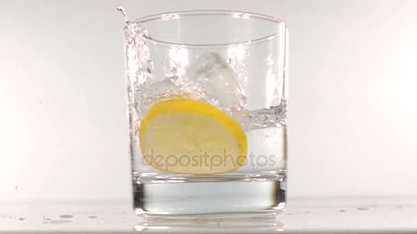 ice falls into a glass of water slow motion - Filmati, video