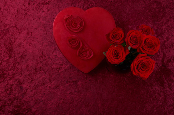 Escena de San Valentín con caja de chocolate en forma de corazón, racimo de rosas sobre fondo de terciopelo triturado rojo y corredor de encaje blanco
 - Foto, Imagen