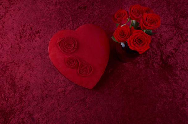 Escena de San Valentín con caja de chocolate en forma de corazón, racimo de rosas sobre fondo de terciopelo triturado rojo y corredor de encaje blanco
 - Foto, imagen