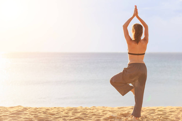 Kadın oyun Yoga ve egzersiz günbatımı, tropikal sahilinde  - Fotoğraf, Görsel