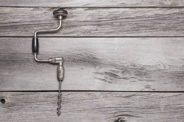 A vintage brace and bit on a rustic wooden background. - Foto, immagini