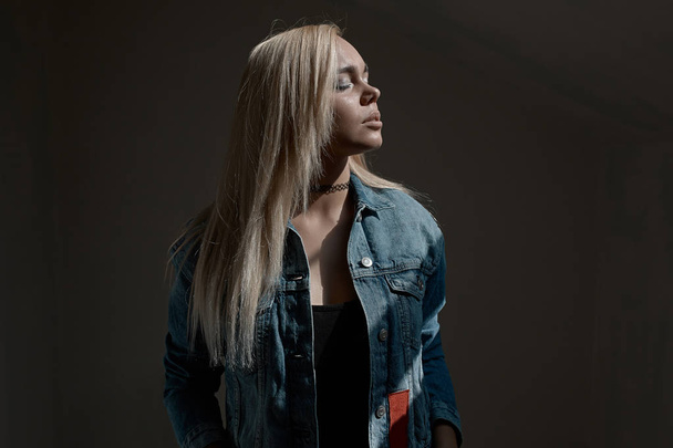 Portret van jonge blonde vrouw op donkere achtergrond - Foto, afbeelding