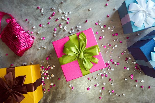 Top view of colorful gift boxes with little pink stars on grey background - Fotografie, Obrázek