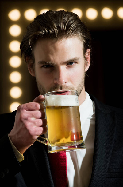beer. man or businessman with beard and hairstyle in formal outfit with red tie hold glass near mirror with lamps, meeting and relax, bar and restaurant, tasting and degustation - Φωτογραφία, εικόνα