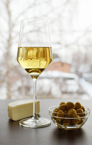 Glas witte wijn Piala olijven kaas suluguni op winter achtergrond - Foto, afbeelding