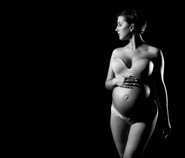 pretty pregnant woman with round belly isolated on black - Фото, изображение