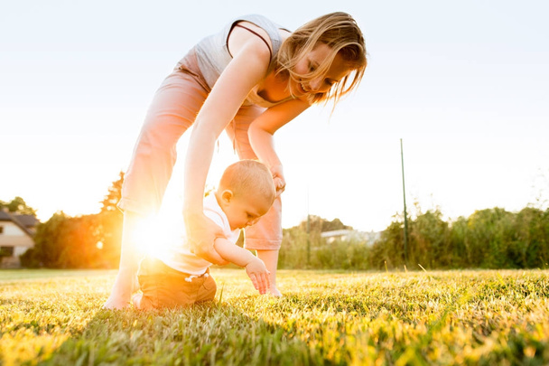 Baby boy with his mother outside in the garden. - 写真・画像