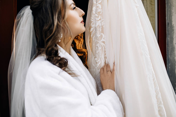 Beautiful bride stands before a rich wedding dress - 写真・画像