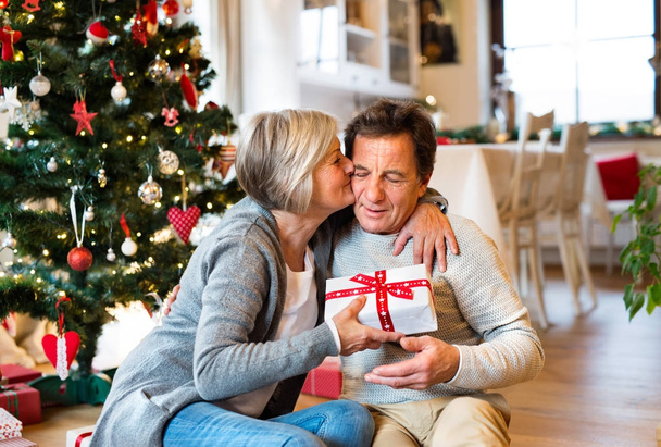Senior couple in front of Christmas tree with presents. - Foto, Bild