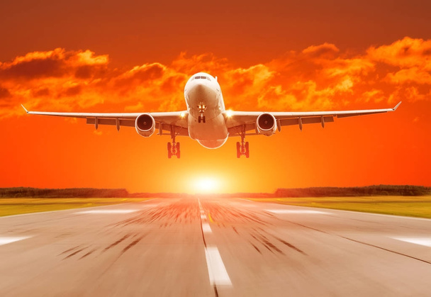 Passagierflugzeug landet bei Sonnenuntergang auf Landebahn. - Foto, Bild