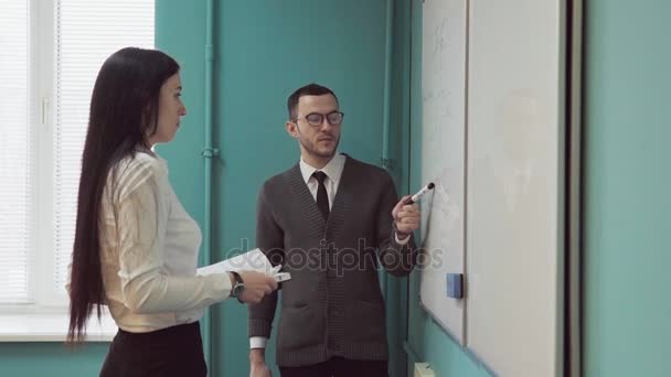 Business man and woman discussing something near whiteboard - Filmati, video