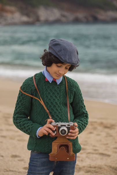 Tinédzser fárasztó, lapos sapka, és zöld pulóver, vintage film fényképezőgép tartja a kezében. Függőleges összetétele. - Fotó, kép