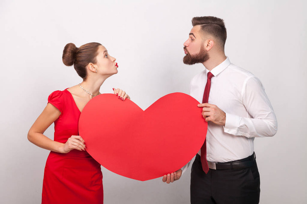 couple holding heart and sending each other air kiss on gray background, valentines day concept  - Fotoğraf, Görsel