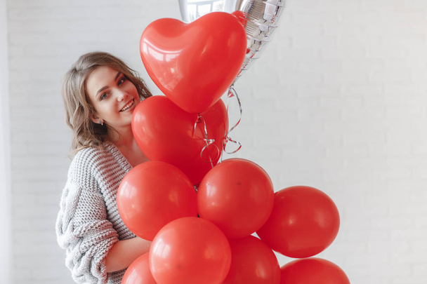 Valentine Beauty girl with colorful air balloons laughing, isolated on background. Beautiful Happy Young woman. holiday party. Joyful model having fun, playing and celebrating with red color balloon - Foto, imagen
