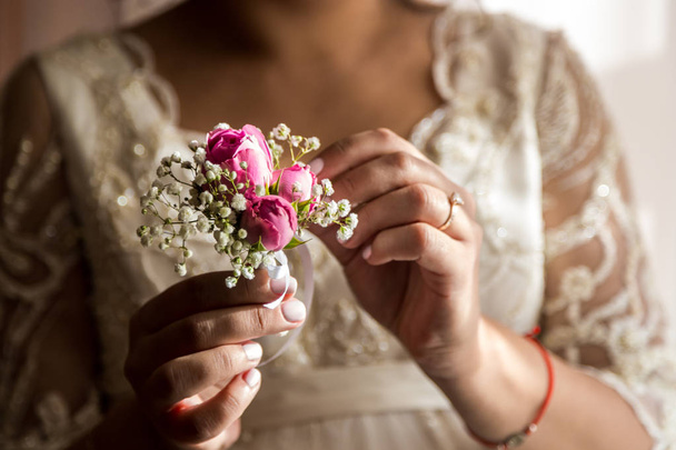 Novia sosteniendo un ojal. La mano tierna de la novia que sostiene boutonniere para el novio - Foto, imagen