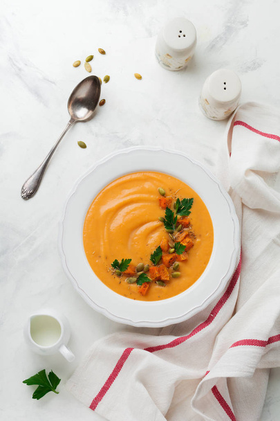 Homemade pumpkin soup in white ceramic dish on an old concrete or stone background. Selective focus.  Top view. Copy space. - 写真・画像