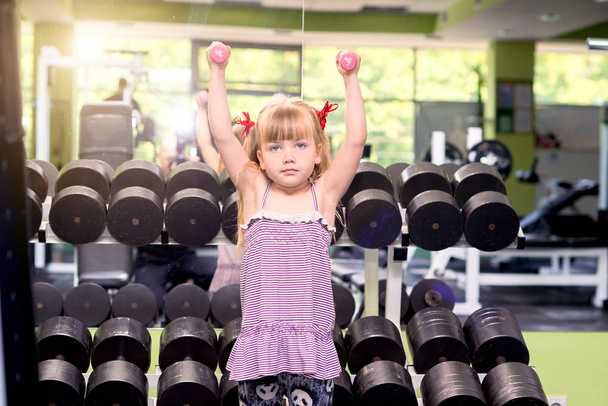 Little girl with dumbbells in the gym - Фото, изображение