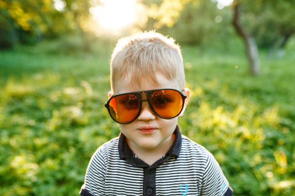funny little Boy in yellow sunglasses in summer park - Foto, Imagem