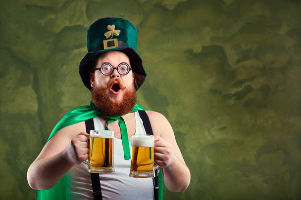 A fat man with a beard in St. Patricks suit is smiling with a m - Φωτογραφία, εικόνα