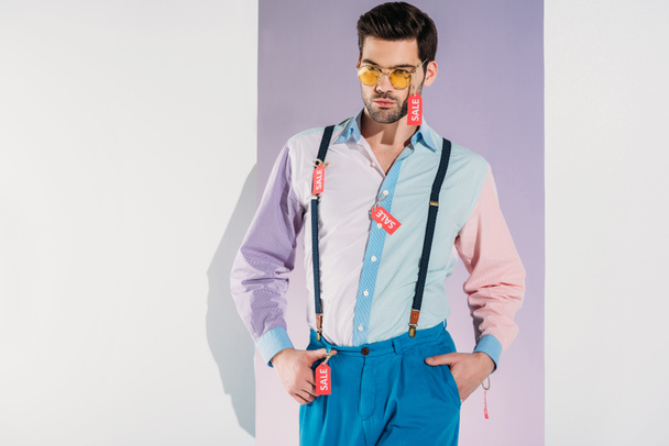 Satılık ile şık giysiler içinde yakışıklı adam ayakta beyaz izole Etiketler - Fotoğraf, Görsel