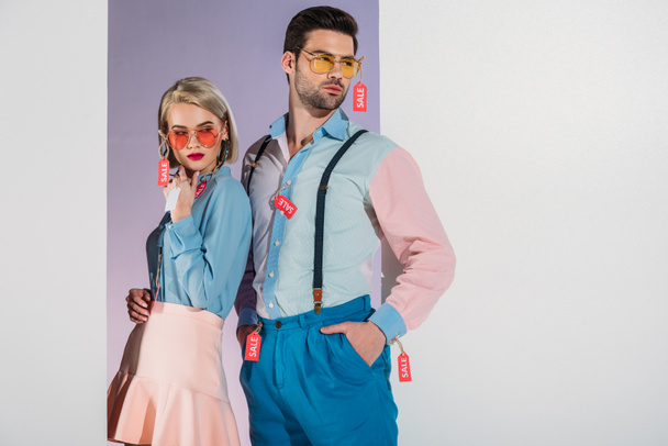 atractiva pareja en ropa de moda con etiquetas de venta aisladas en blanco
 - Foto, Imagen