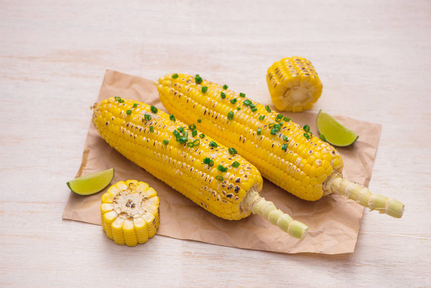 Delicioso maíz a la parrilla sabroso en la mesa de madera, vista superior
 - Foto, Imagen