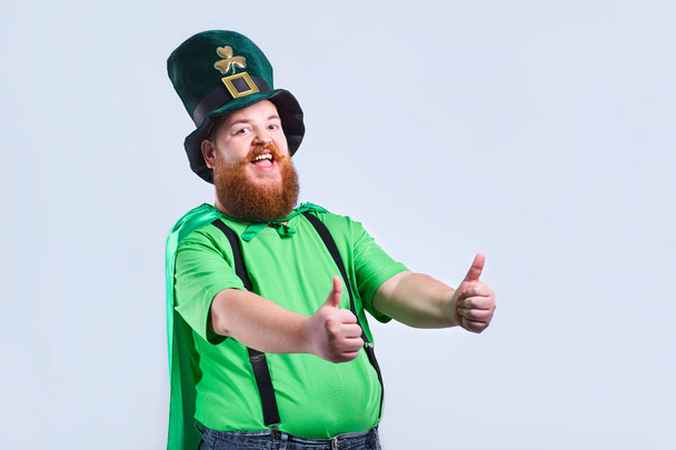 Un hombre gordo con barba en traje de San Patricio sonríe con una m
 - Foto, Imagen