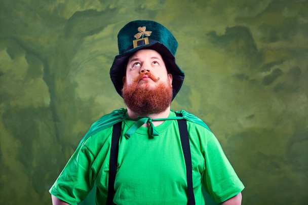 A fat man with a beard in St. Patricks suit is smiling. - Photo, image
