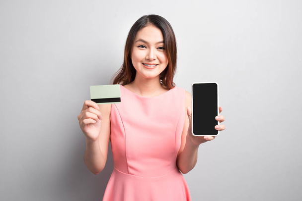 Чарівна азіатська жінка рука тримає смартфон і показує кредитну картку
. - Фото, зображення