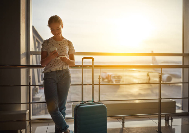 Nuori nainen odottaa lentävät lentokentällä ikkunan kanssa suitcas
 - Valokuva, kuva
