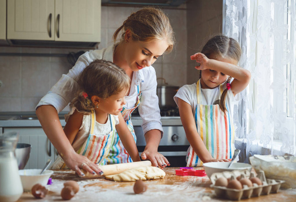 Mère de famille heureuse et les enfants jumeaux font cuire la pâte à pétrir dans
  - Photo, image