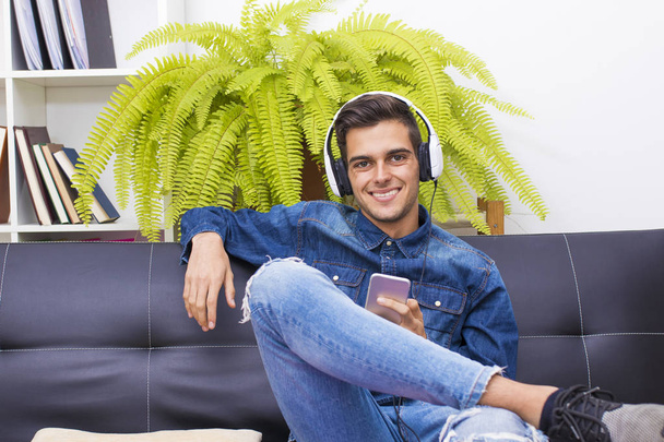 молодий чоловік слухає музику вдома Лаунж з навушниками
 - Фото, зображення
