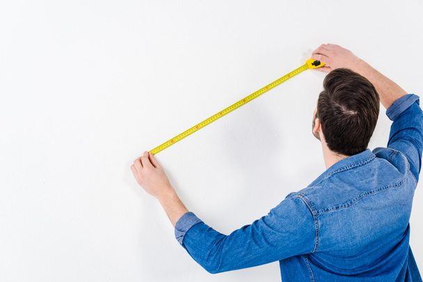 vista trasera de la pared de medición del hombre con cinta métrica en blanco
 - Foto, Imagen