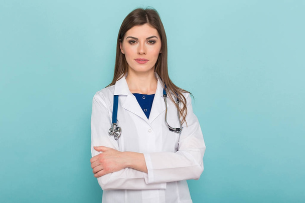 Уверенная молодая женщина-врач со стетоскопом смотрит в камеру на синем фоне
  - Фото, изображение