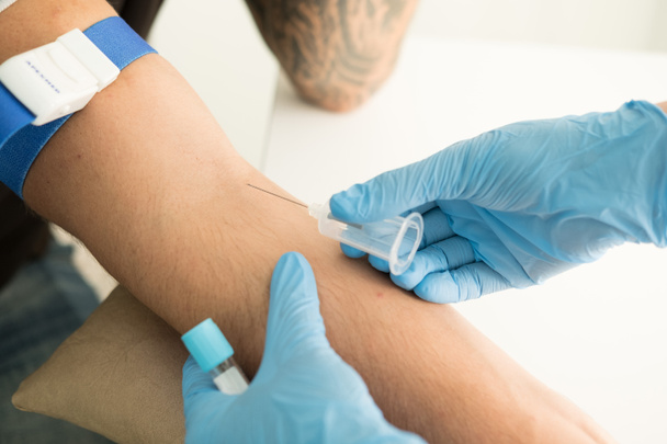 Close up nurse pricking needle syringe in the arm patient drawing blood sample for blood test - Foto, Imagem